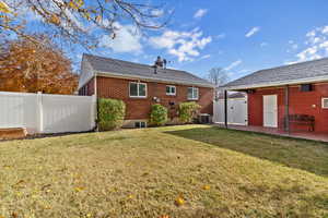 Rear view of property with brick siding, a chimney, a gate, and a patio