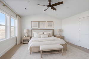 Spacious owners suite featuring lofted ceiling, a ceiling fan, carpet and natural light