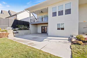 Rear view of property featuring a ceiling fan, stucco siding, a patio, and a balcony