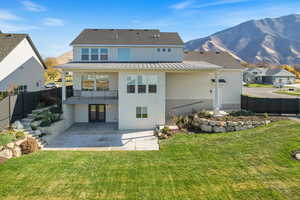 Rear view of house with stucco siding, a patio, a balcony, and a fenced backyard