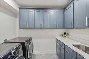 Washroom featuring washer and clothes dryer, beautiful counter tops and cabinets. tile patterned floors, and cabinet space