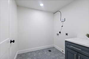 Laundry area featuring electric dryer hookup, hookup for a washing machine, tile patterned flooring, and cabinet space