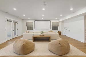 Cinema with recessed lighting, light wood-style flooring, and french doors