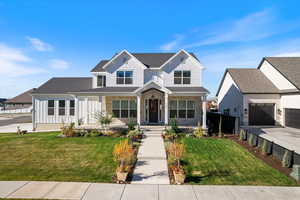 View of front of house with covered porch, a front lawn, board and batten siding, and a garage