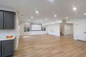 Living room/ Theater room with recessed lighting, light wood finished floors, and stairs
