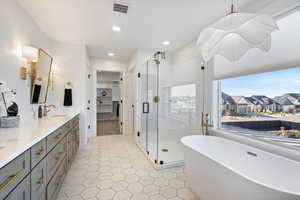 Owners full bath with a freestanding bath, a shower stall, double vanity, a spacious closet, and luxury lighting.