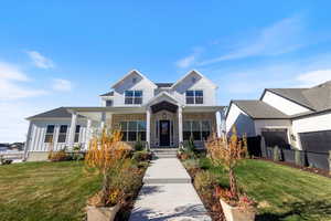 View of front of property with covered porch, a front yard, and stone siding