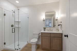 Bathroom with vanity, beautiful cabinets and counter tops,  a stall shower, light wood-style flooring, and recessed lighting
