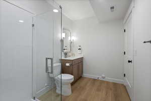 Bathroom featuring light wood-style flooring, vanity, and a shower stall