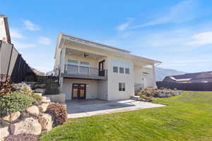 Rear view of house with a mountain view, french doors, stucco siding, a ceiling fan, and a balcony