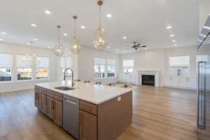 Kitchen featuring open floor plan, a fireplace, appliances with stainless steel finishes, hanging light fixtures, and recessed lighting