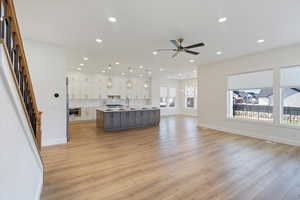 Kitchen featuring white cabinets, open floor plan, hanging light fixtures, a large island, and recessed lighting