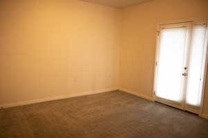 Unfurnished room with dark colored carpet and baseboards