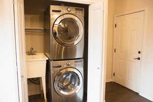 Laundry room with estacked washer and dryer and dark wood-type flooring