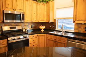 Kitchen featuring stainless steel appliances, decorative backsplash, and tile counters