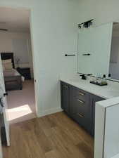 Full bathroom with ensuite bathroom, double vanity, and light wood-style flooring