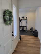 Exercise area with light wood finished floors and recessed lighting