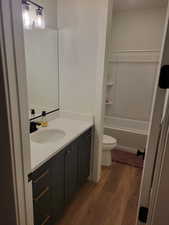 Bathroom with dark wood-type flooring, vanity, and shower / bathtub combination