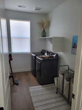 Washroom with dark wood-style flooring and washing machine and clothes dryer