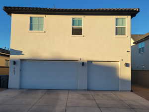 View of front of home with stucco siding, an attached garage, and driveway