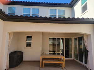 Rear view of property featuring a patio area, a tile roof, and stucco siding