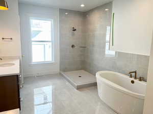 Bathroom with a freestanding tub, light tile patterned floors, vanity, a tile shower, and tile walls
