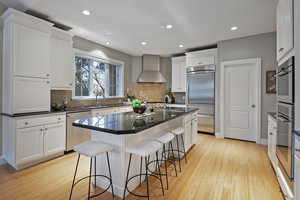 Kitchen with white cabinetry, an island with sink, dark stone countertops, appliances with stainless steel finishes, and recessed lighting