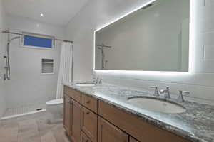 Full bathroom with double vanity, a stall shower, and tile walls