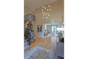 Foyer entrance featuring arched walkways, a high ceiling, stairs, and wood finished floors