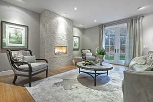 Sitting room with wood finished floors, french doors, a large fireplace, and recessed lighting