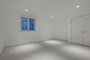 Unfurnished bedroom with light carpet, recessed lighting, and a closet