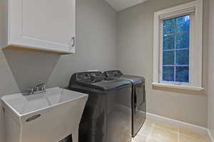 Washroom with independent washer and dryer, cabinet space, and light tile patterned flooring