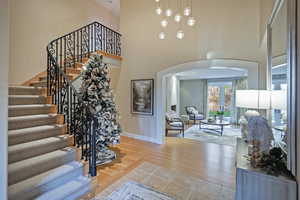 Foyer entrance with arched walkways, wood finished floors, french doors, stairway, and a towering ceiling