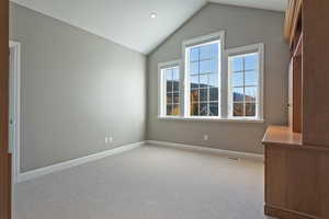 Spare room with light colored carpet and lofted ceiling