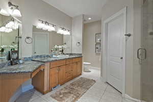 Bathroom featuring double vanity, light tile patterned flooring, recessed lighting, and a stall shower