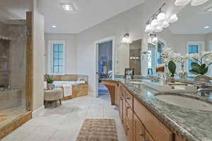 Full bath featuring ensuite bath, double vanity, light tile patterned floors, a garden tub, and healthy amount of natural light