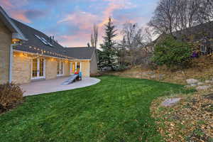 View of green lawn featuring a patio and french doors