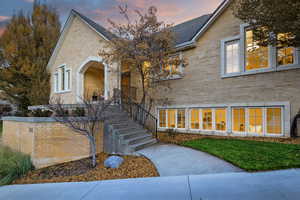 View of front of home featuring brick siding, stairway, and a yard