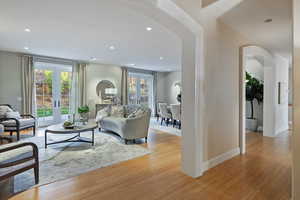 Living room featuring arched walkways, plenty of natural light, light wood-type flooring, and recessed lighting