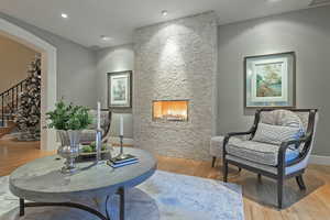 Sitting room with light wood finished floors, a fireplace, recessed lighting, and arched walkways