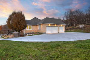 View of front of home with brick siding, driveway, a front yard, and an attached garage