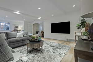Living room with light wood-style floors, recessed lighting, and beam ceiling