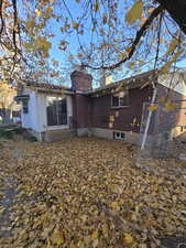 Back of house with a chimney, brick siding, and entry steps