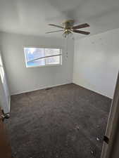 Empty room with dark carpet and a ceiling fan
