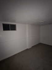 Unfurnished room featuring dark colored carpet and baseboards