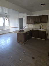 Kitchen with a textured ceiling, light countertops, a peninsula, dark wood finished floors, and dark brown cabinetry