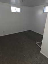 Basement featuring dark carpet and a textured ceiling