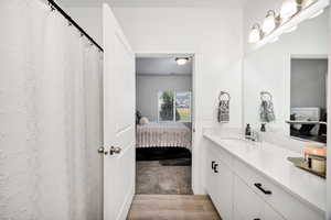 Ensuite bathroom featuring curtained shower, vanity, and light wood finished floors