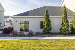 View of side of property featuring a yard, stucco siding, and roof with shingles