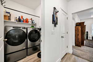 Laundry room with light wood-style flooring and washer and dryer